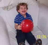 Mark smiling in chair while holding balloon